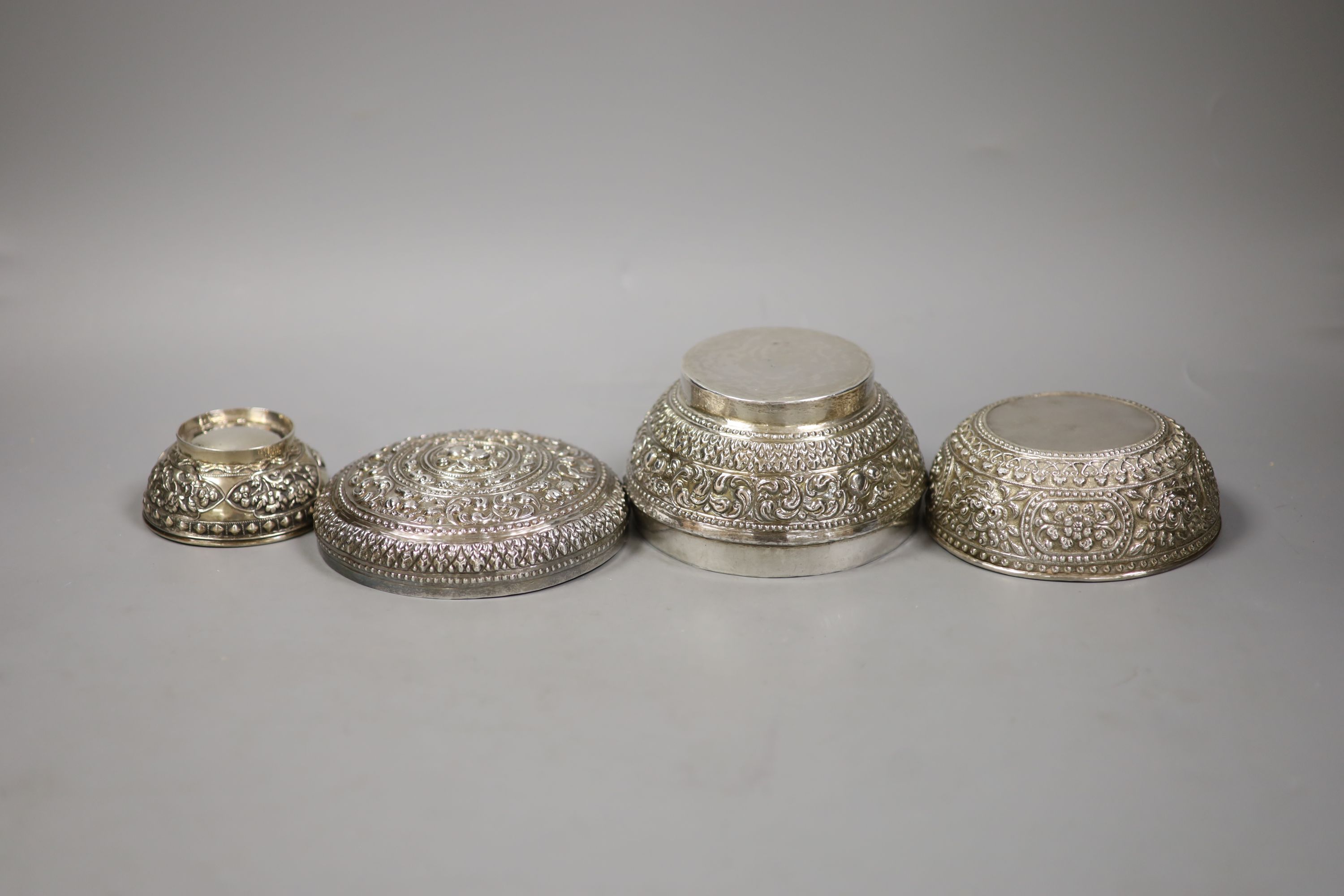 An Indonesian embossed white metal bowl and cover and two similar smaller bowls, largest diameter 13.5cm